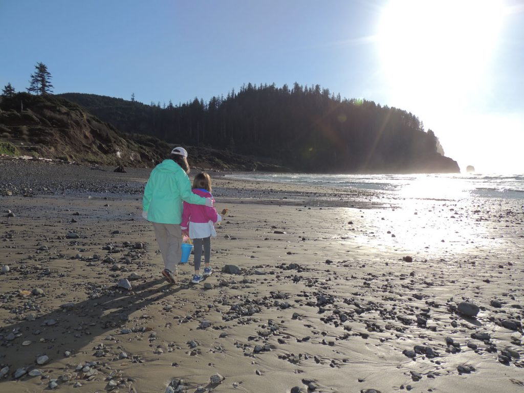 Woman and child walk along rocky beach at low tide