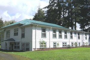 Long white building next to pine trees