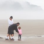 Man, woman and child stand on beach in fog